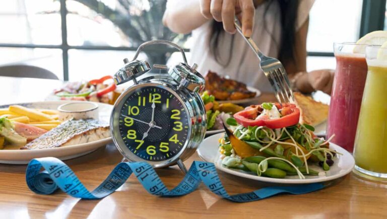 Selective focus of Alarm Clock with woman hand and fork which re